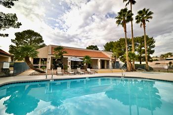 A swimming pool in front of a building with palm trees.